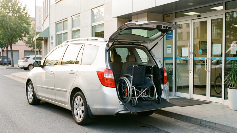Taxi médical accessible stationné devant l’entrée d’une clinique, avec un fauteuil roulant plié visible à l’intérieur.